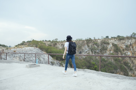 侧视图-年轻的亚泰黑头发旅行家妇女戴着帽子在山区户外散步。