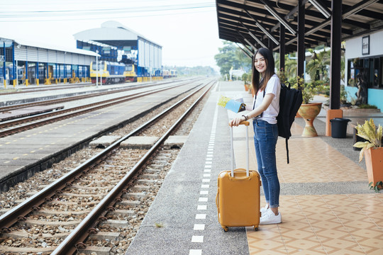 一位年轻的亚裔泰国长黑发女旅客在车站月台等火车。