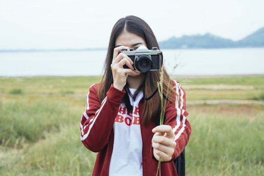 特写镜头——年轻的亚泰黑头发旅行家妇女用相机拍摄野生植物花。