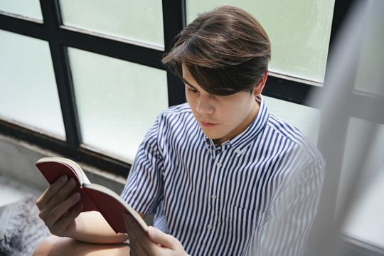 在大学校园里，亚洲年轻学生正在读一本准备考试的书。