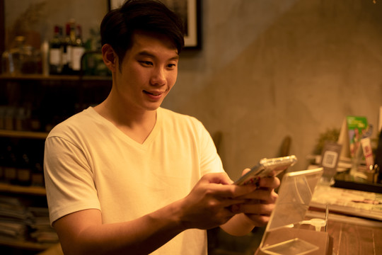 亚洲年轻人在酒吧用智能手机点饮料和食物。