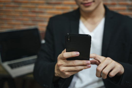 穿着黑色西装的商人使用智能手机在互联网上搜索信息。