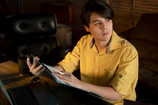 亚洲年轻商人晚上独自在办公室加班。