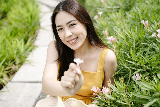 身着黄色连衣裙的亚洲美女在乡村农场采花的肖像。