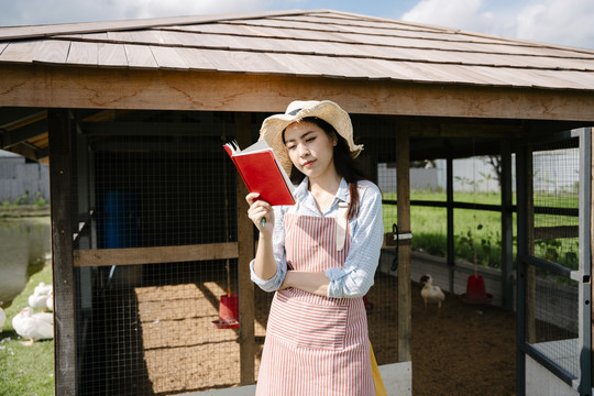 美丽的亚洲农妇在自家鸡舍农场检查动物健康。