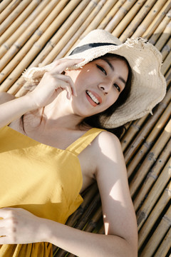 美丽的亚洲旅行家的画像戴着帽子躺在户外的木凳上。