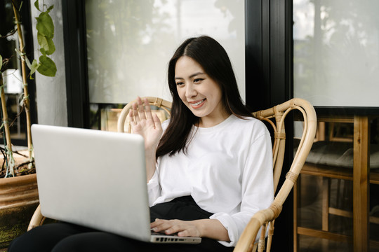 亚洲女性与朋友视频通话或在笔记本电脑上在线学习。