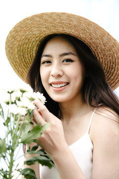 美丽的亚洲旅行家妇女的肖像，戴着白花帽子。