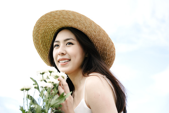 美丽的亚洲旅行家妇女的肖像，戴着白花帽子。