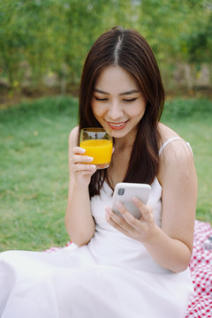 美丽的亚洲女旅行家用橙汁自拍的肖像。