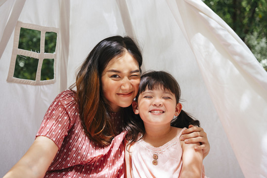 院子里白色帐篷里的亚洲母亲和女儿的肖像。