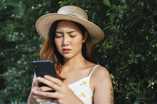 不开心的亚洲女人带着愤怒的表情在智能手机上发短信。