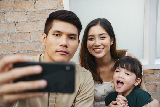 亚洲家庭在家用智能手机自拍的照片。