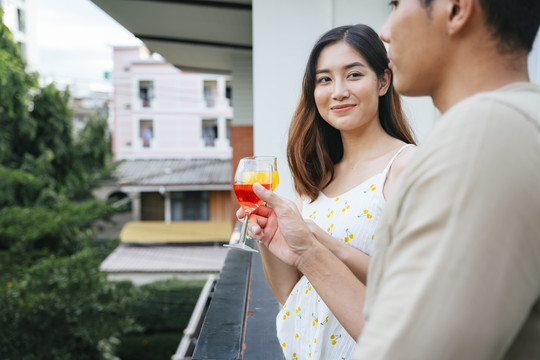 亚洲女人在派对上爱上一个男人。两人在房子的阳台上交谈。