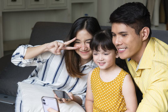 亚洲家庭在客厅用智能手机自拍。