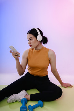 年轻的亚洲女性在健身房休息后听音乐。