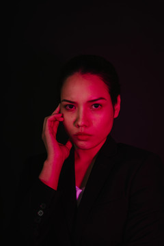 黑色背景下霓虹灯下年轻亚洲黑发女性的特写肖像。