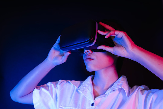 亚洲女性佩戴现代VR护目镜，与游戏或3D视频交互。