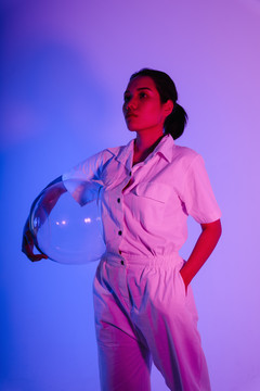 霓虹灯下戴着太空头盔的亚洲女宇航员肖像。