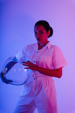 霓虹灯下戴着太空头盔的亚洲女宇航员肖像。