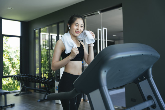 健康的亚洲女性在健身房的跑步机上跑步。