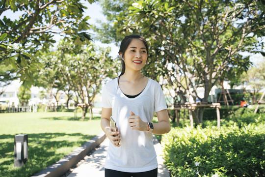 夏季在公园小路上跑步或慢跑的运动型亚洲女性。