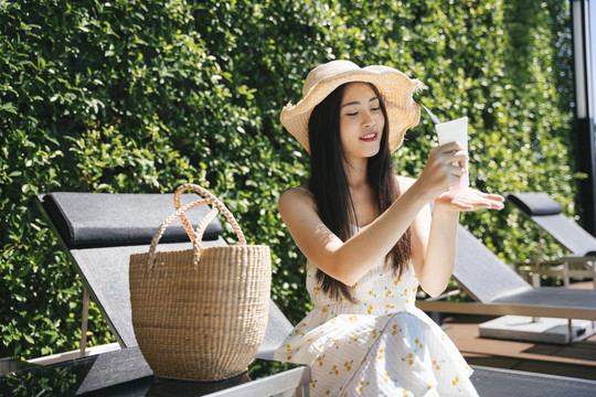 美丽的亚洲女性旅行者在身体皮肤上涂抹白色乳液。