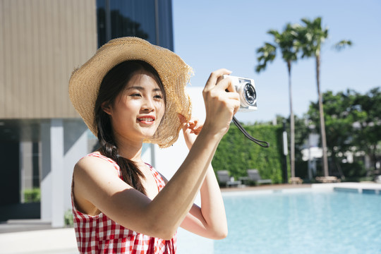 美丽的亚洲女人戴着帽子用相机拍照的肖像。