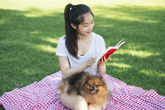 主人在公园为她的狗读书。和可爱的宠物野餐。