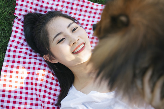 女主人把狗举到空中，在公园里玩得很开心。