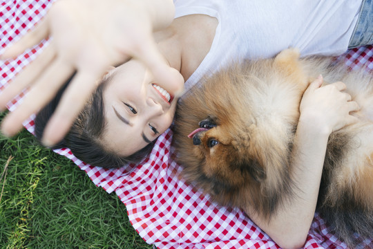 俯视图-女主人和她的狗一起躺在公园里。