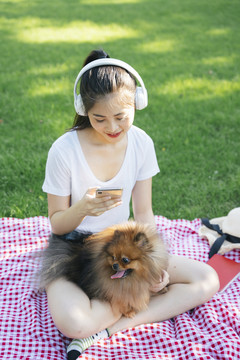 夏天，亚洲女人和波美拉尼亚斯皮茨犬在公园里玩耍。