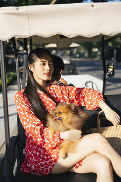 美丽的亚洲女人和她的狗坐在夕阳下的客运穿梭车上。