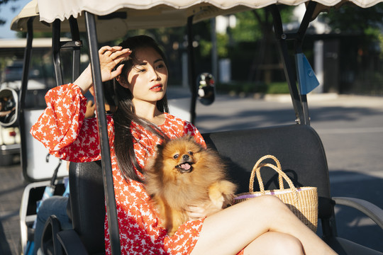美丽的亚洲女人和她的狗坐在夕阳下的客运穿梭车上。