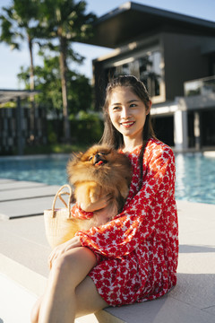 亚洲女人的肖像，穿着红色连衣裙和波美拉尼亚斯皮茨犬。