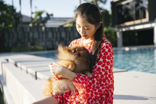 亚洲女人的肖像，穿着红色连衣裙和波美拉尼亚斯皮茨犬。