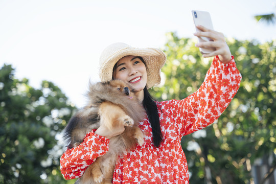 美丽的亚洲女旅行家带着她的狗进行自拍旅行。