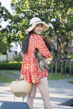 美丽的亚洲女旅行者带着她的狗在度假村和酒店里旅行。
