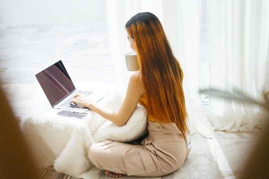 后视图-自由职业女性，操作笔记本电脑，喝咖啡。