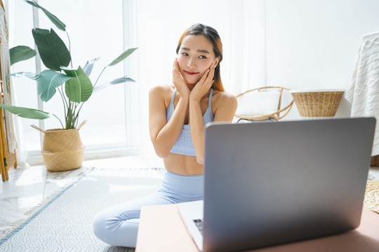 美丽的运动型女士在网上讲授瑜伽课程。她在笔记本电脑上看在线瑜伽课。