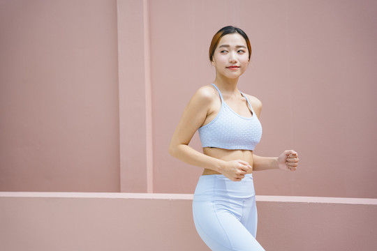 美丽的运动型亚洲女性，穿着运动胸罩和跑步姿势。