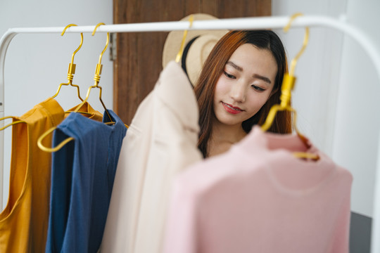 美丽的年轻亚洲女人在购物中心买衣服。