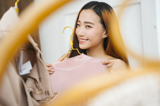 美丽的年轻亚洲女人在购物中心买衣服。