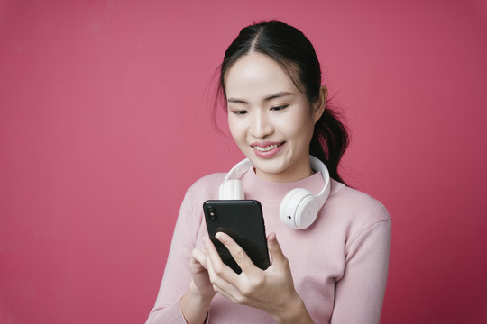在音乐流媒体应用程序上搜索歌曲的年轻亚洲女性肖像。