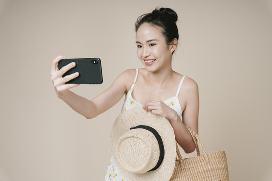 年轻亚洲女旅行者的肖像，用智能手机进行自拍。