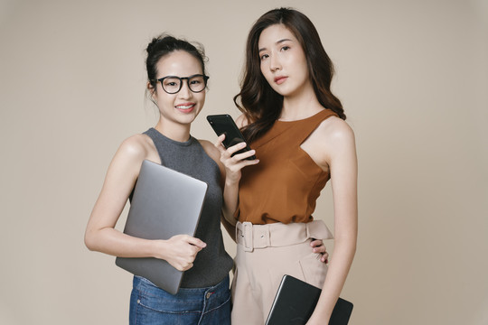 两位穿着休闲衬衫的亚洲女商人站在一起的肖像。