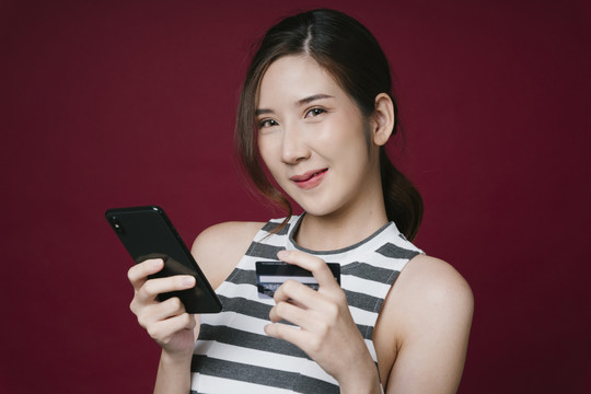 使用智能手机和信用卡进行网上购物的美丽年轻亚洲女性的特写照片