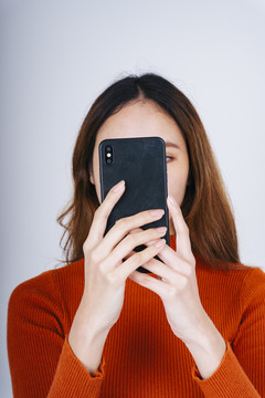 亚洲女性手持智能手机的特写镜头，在社交平台上与朋友聊天。