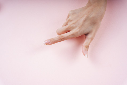 女士用手指着粉色背景上的空白区域。
