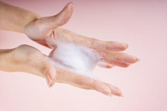 女性手部涂抹护肤霜或面部护理液。